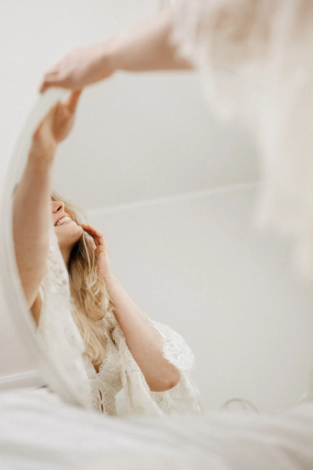 Spiegelbild einer lachenden Frau in Spitze, verträumte Boudoir-Perspektive