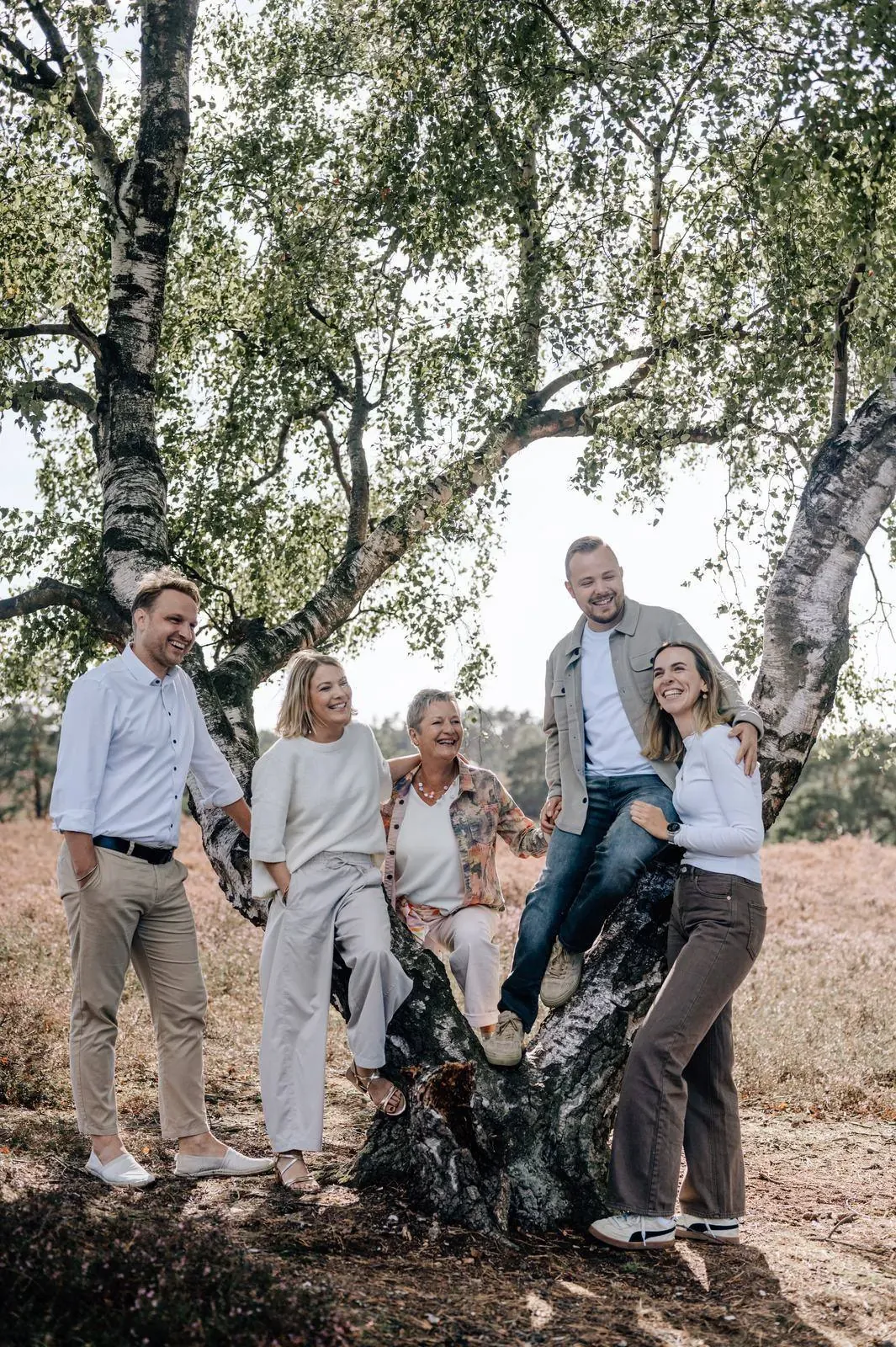 Familie lacht gemeinsam an einer Birke in der Heide, Familienshooting Julia Aßmann