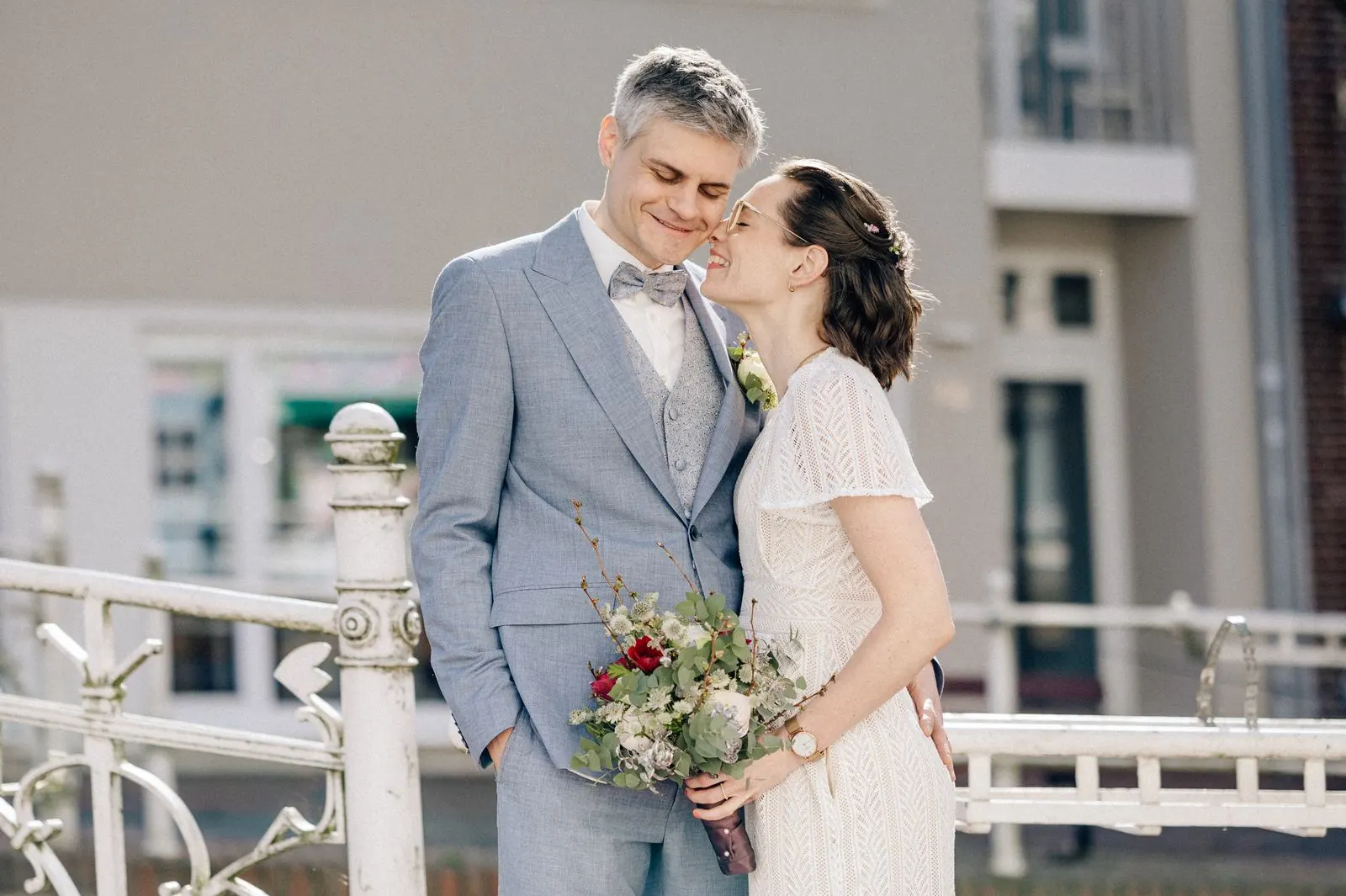 Brautpaar lacht gemeinsam an einem weißen Geländer, Hochzeitsfotografie Julia Aßmann