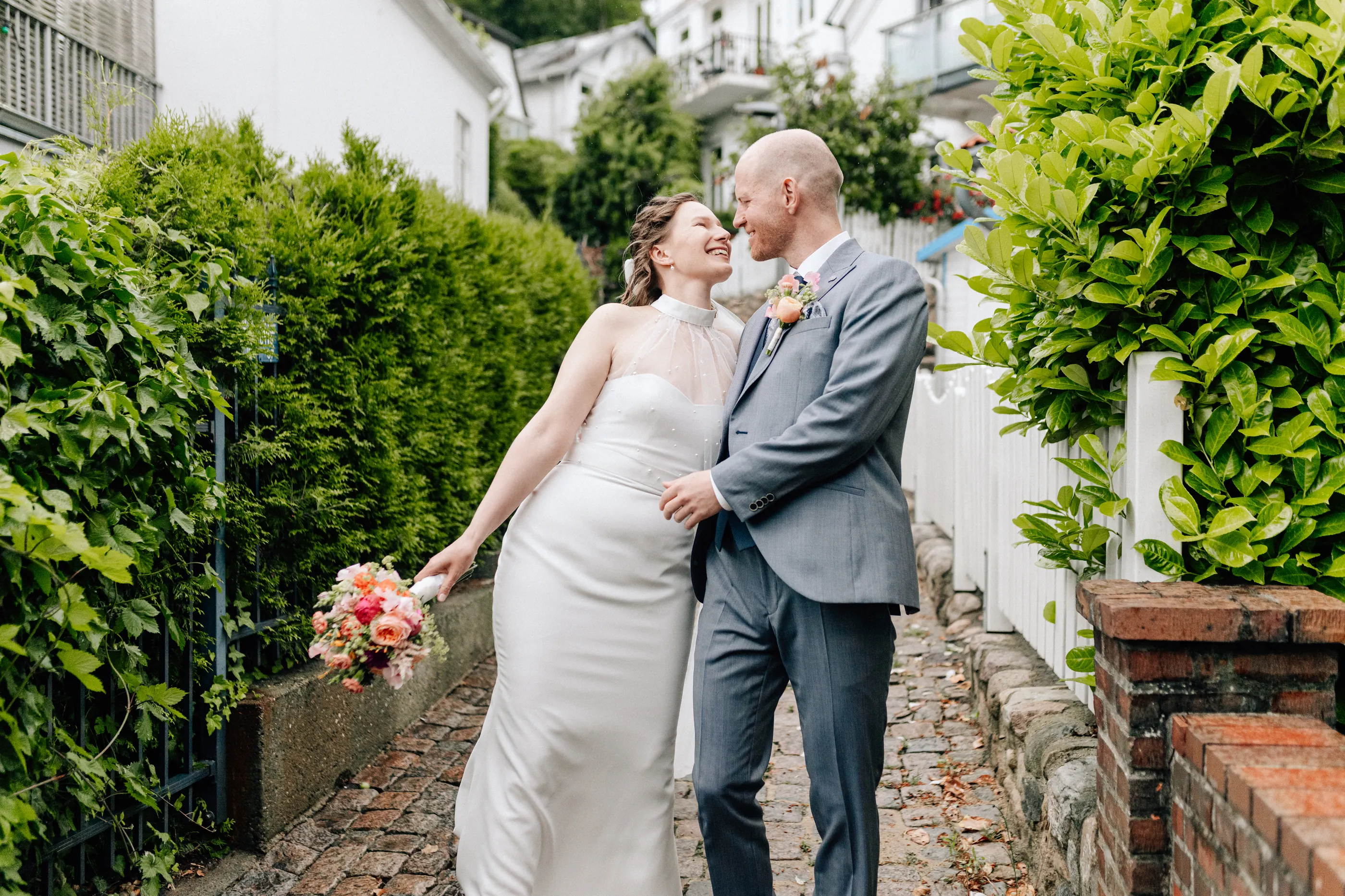 Brautpaar lacht sich in einer grünen Gasse mit Kopfsteinpflaster an, Hochzeitsfotografie Julia Aßmann