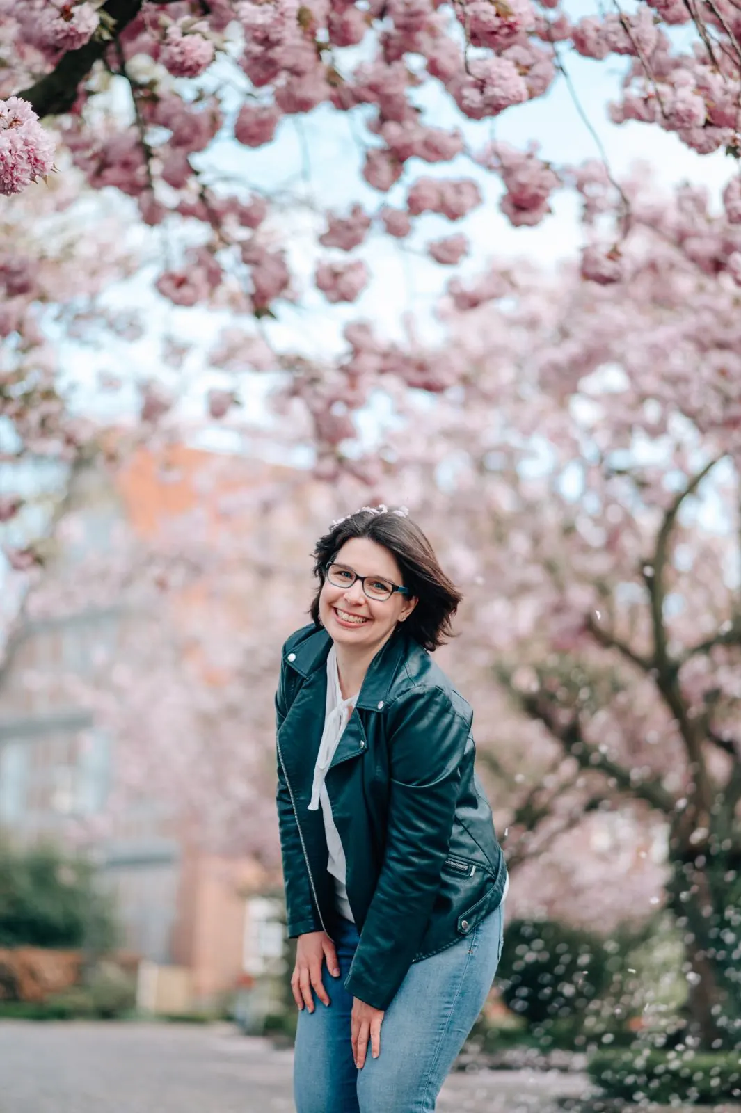 Lachende Frau mit Brille unter rosa Kirschblüten, Portraitshooting im Alten Land
