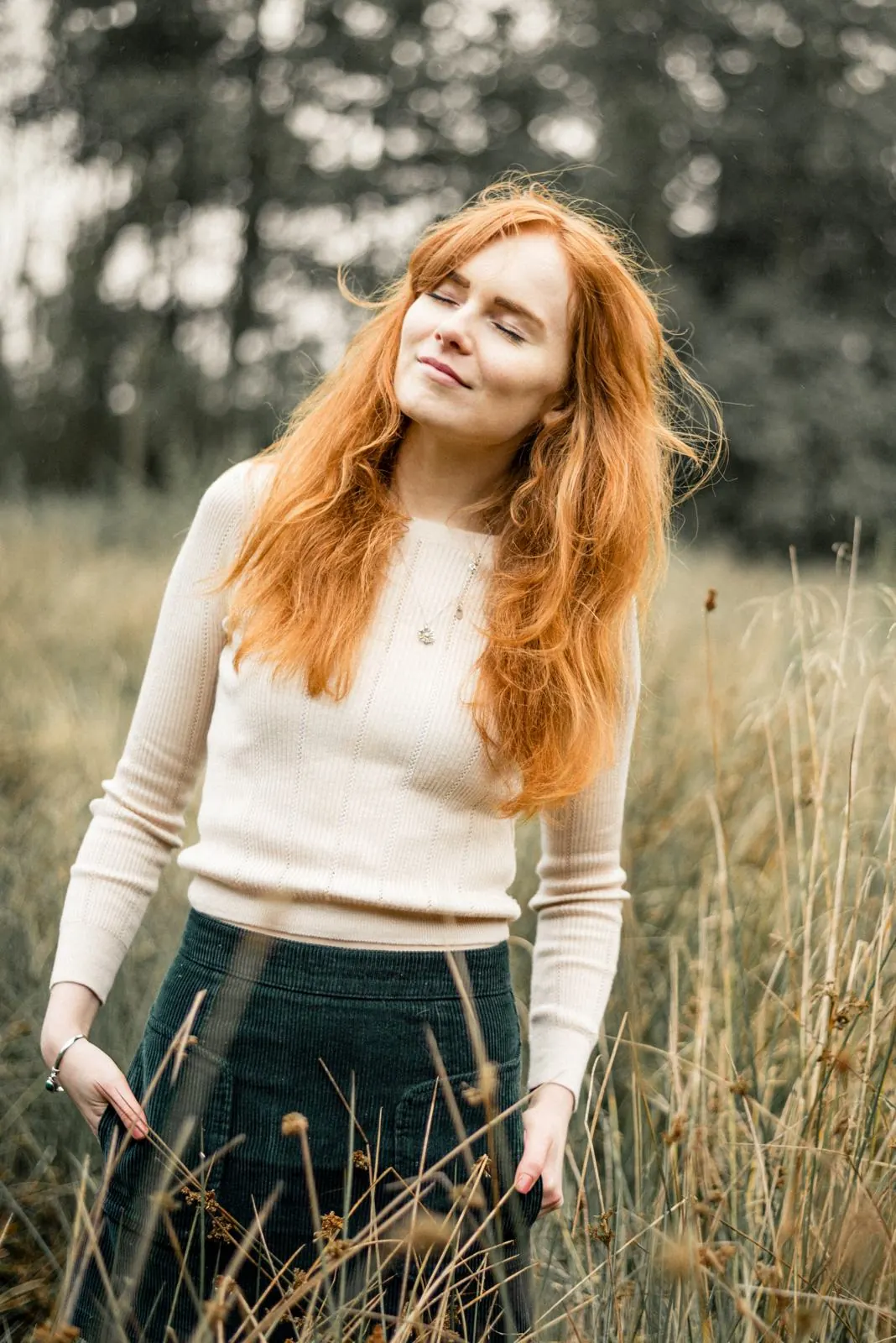 Rothaarige Frau mit geschlossenen Augen im hohen Gras, Outdoor-Portrait