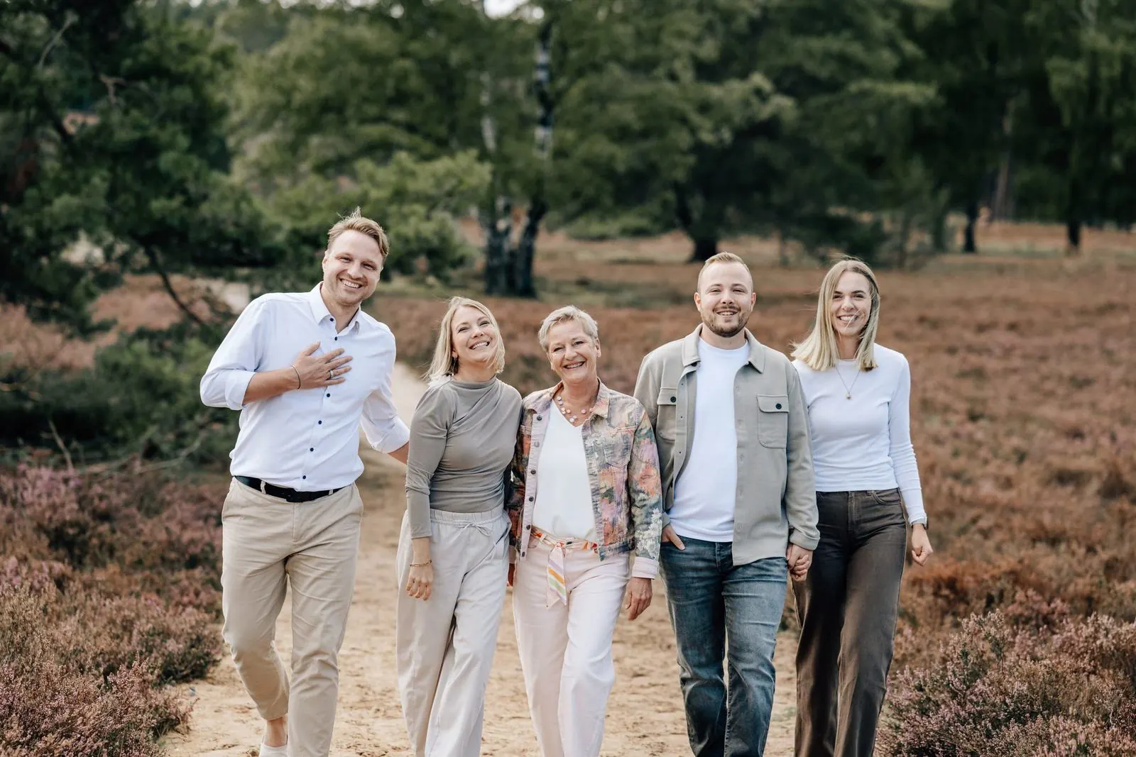 Fünf lachende Familienmitglieder spazieren gemeinsam durch die Fischbeker Heide, Familienfotografie im Alten Land