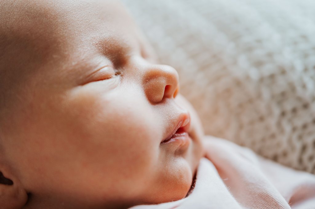 Neugeborenes Baby wird in Nahaufnahme vom Gesicht mit natürlichem Fensterlicht seitlich ausgeleuchtet im Fotostudio für Familienfotografie mit Julia Aßmann Fotografin für Babys, Familien und Schwangere