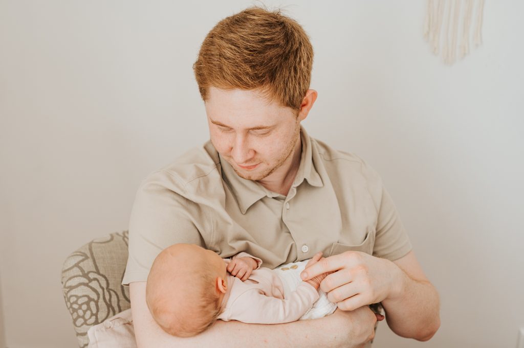 stolzer Vater hält sein Neugeborenes Baby im Arm beim Fotoshooting mit Familie im Fotostudio für Neugeborene von Fotografin Julia Aßmann