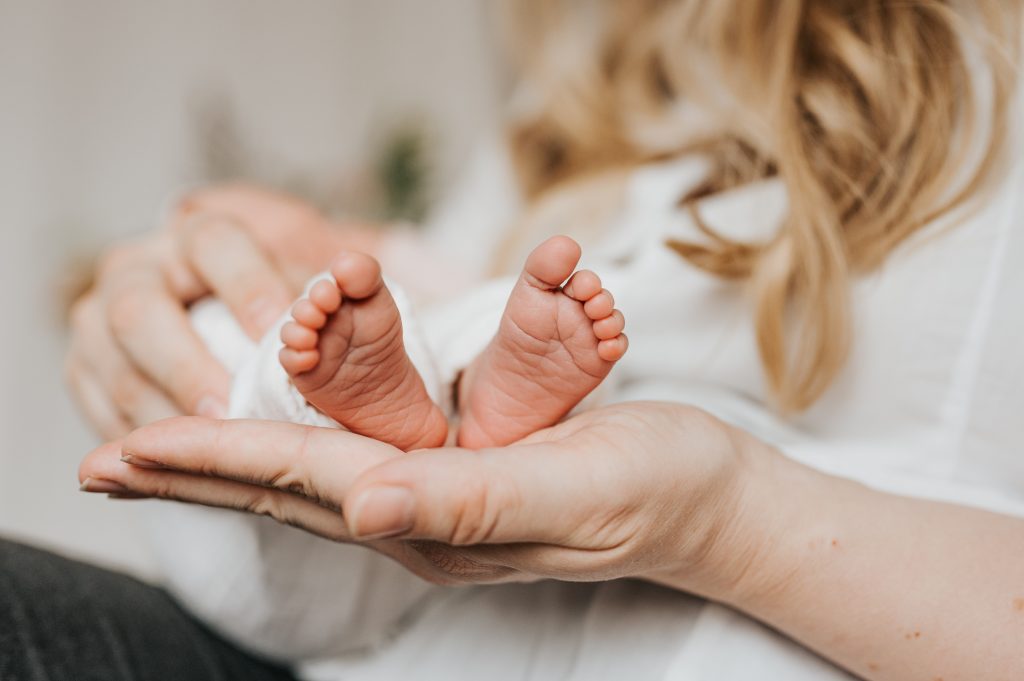 neugeborene Babyfüße liegen auf der Hand der Mutter im Fotostudio in Jork bei Julia Aßmann Fotografie